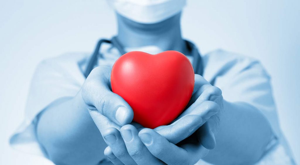 Person hält mit ausgestreckten Händen symbolisch ein rotes Herz nach vorne