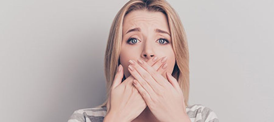 Frau hält sich die Hände vor den Mund