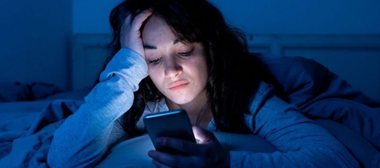 Frau schaut nachts auf ihr Handy