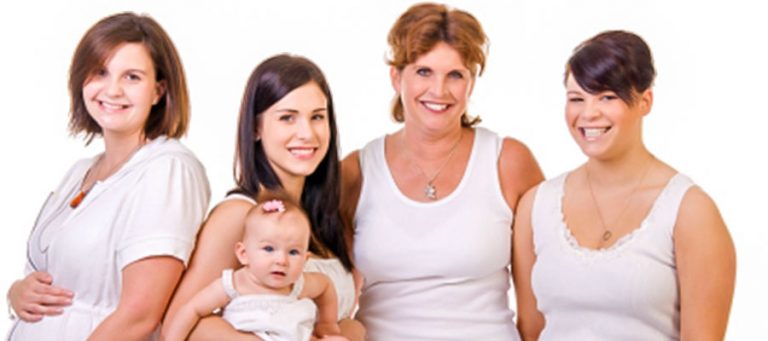 Vier schwnagere Frauen und ein Baby lachen in die Kamera